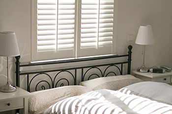 A bedroom with white walls and black iron bed.